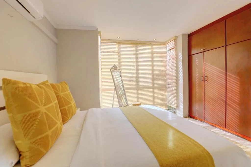Modern bedroom with yellow accent pillows, white bedding, and wooden wardrobes