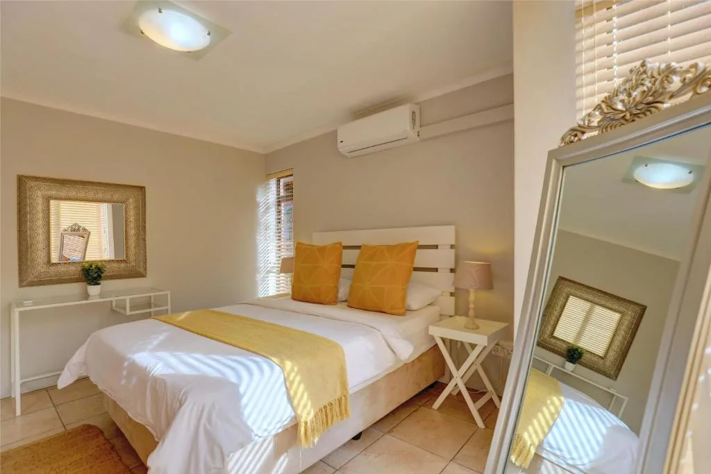 Bright bedroom with white bed, golden yellow cushions and throw blanket
