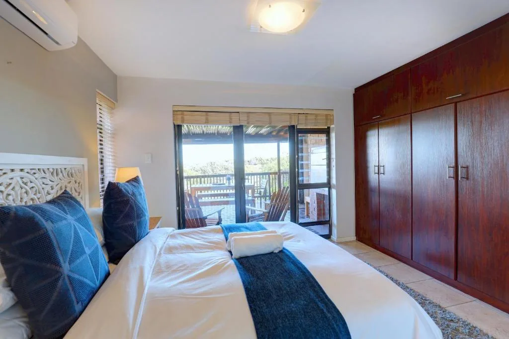 Spacious bedroom with double bed, ocean view doors, and wooden wardrobe