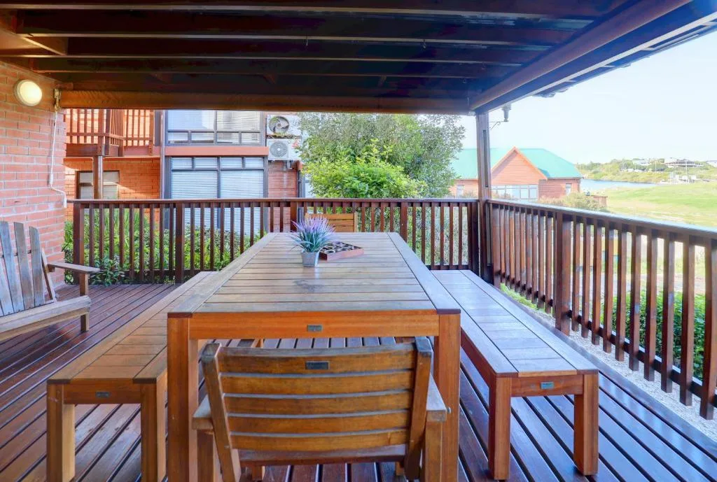 Covered wooden deck with dining table overlooking rural countryside landscape