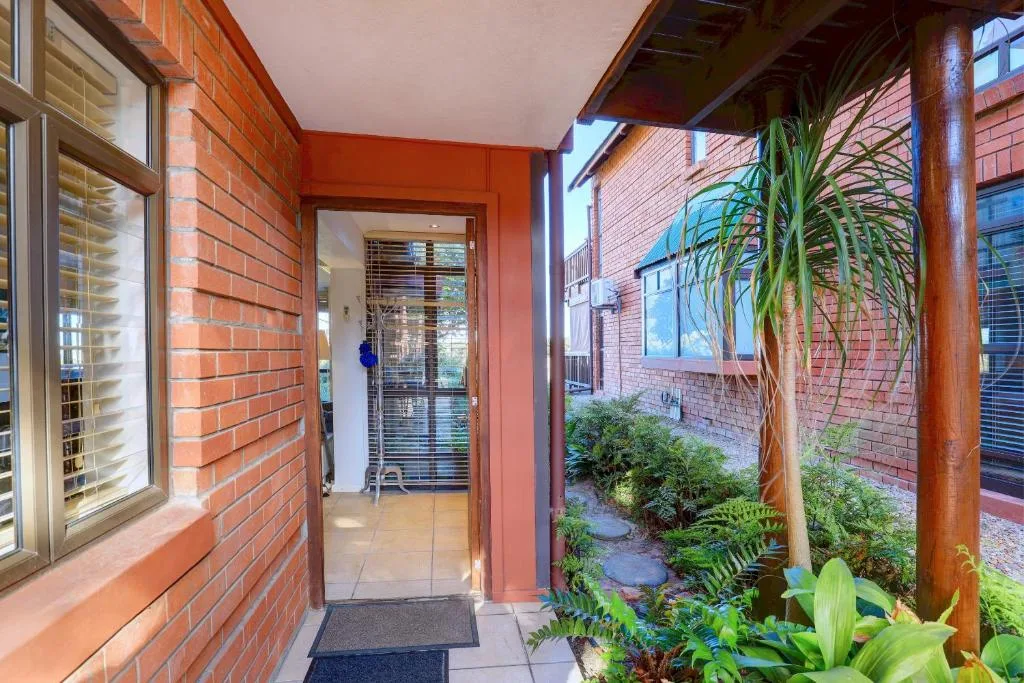 Red brick entrance with covered porch and lush green plants