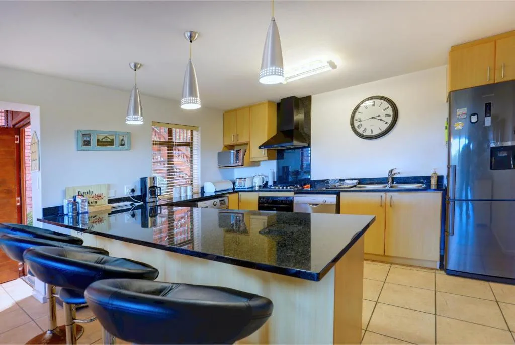 Modern kitchen with yellow cabinetry, dark countertops, and breakfast bar seating