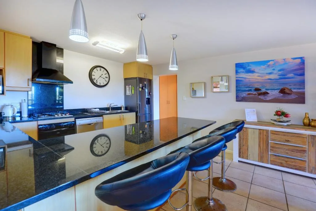 Modern kitchen with yellow cabinetry, island counter, and blue bar stools