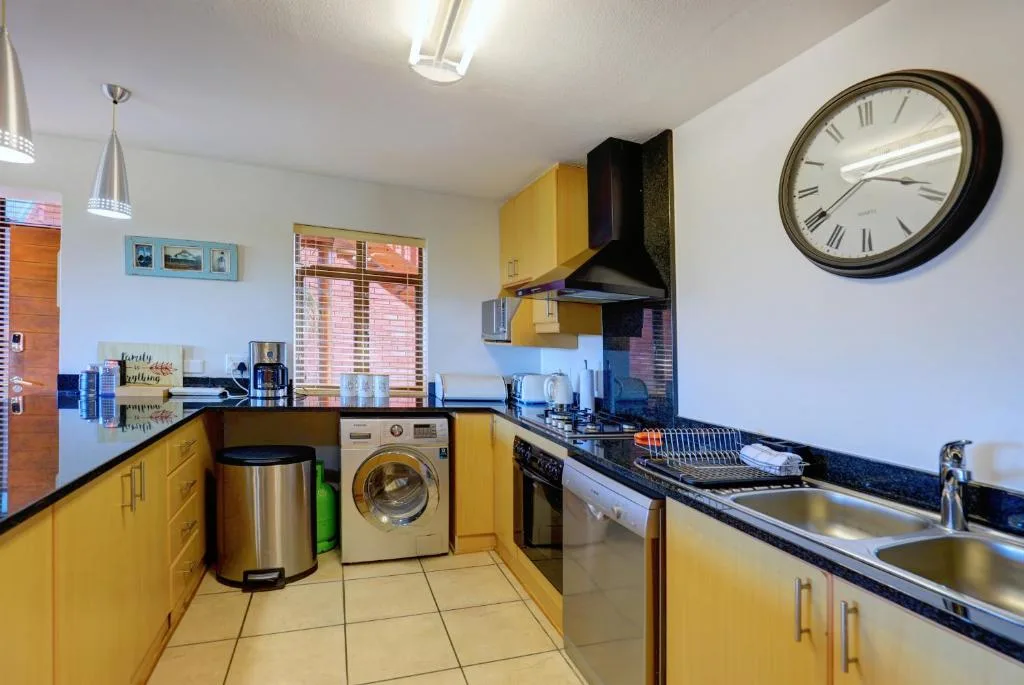 Bright yellow kitchen with black countertops, stove, and stainless steel sink