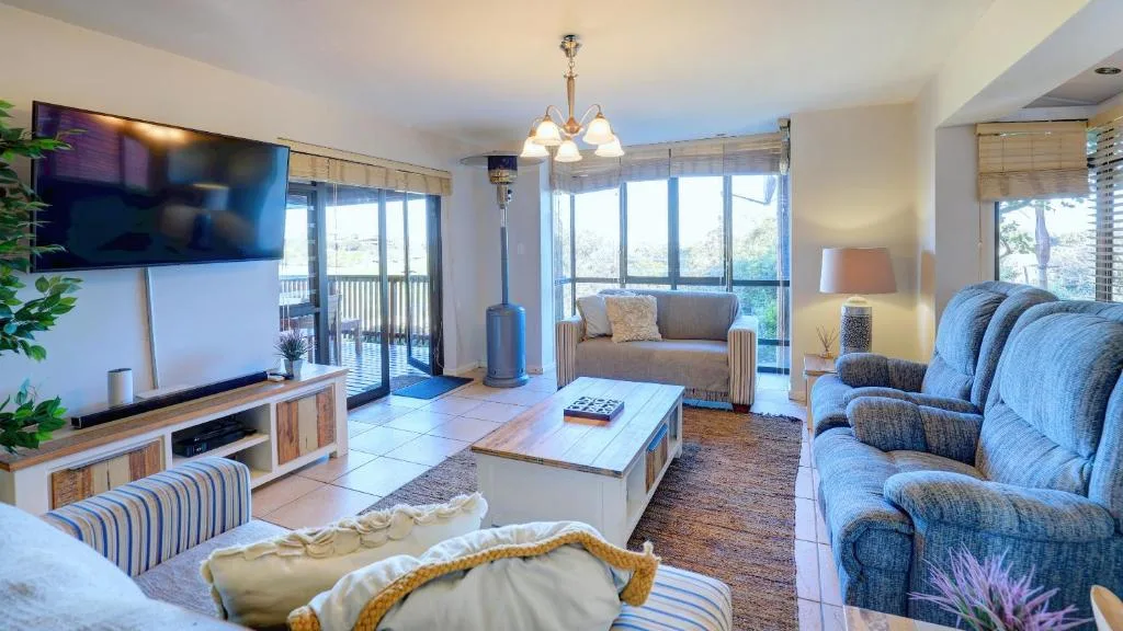 Spacious lounge with blue upholstered seating, TV, and expansive views