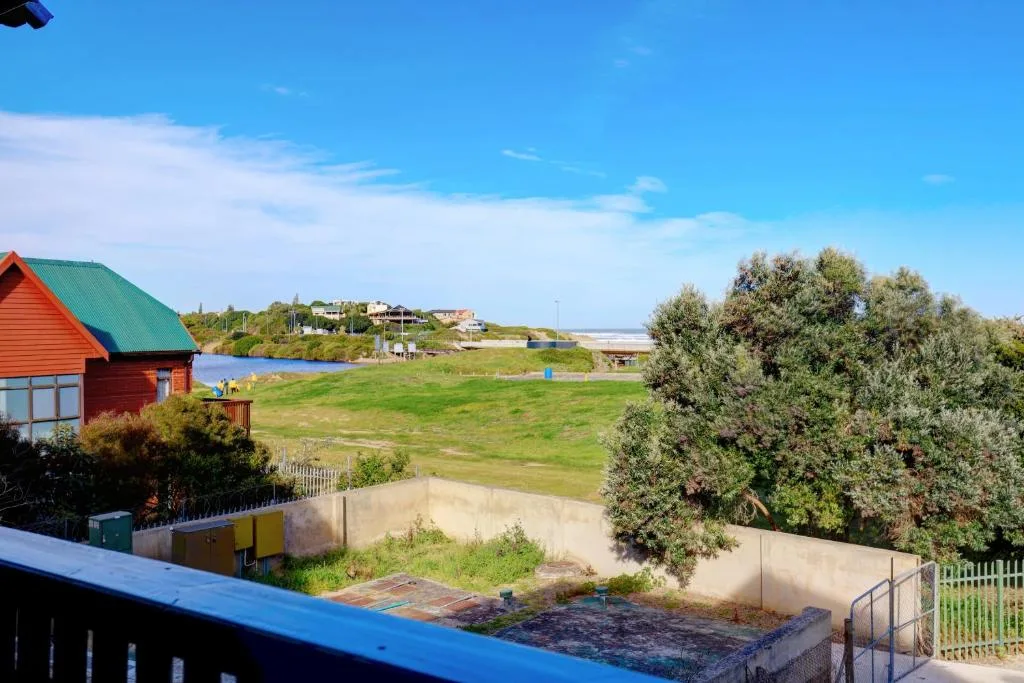 Scenic lagoon and countryside view from property with red cottage and rolling green hills