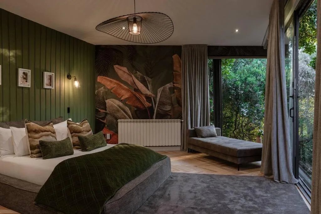 Luxurious bedroom with forest views, green walls, and botanical artwork