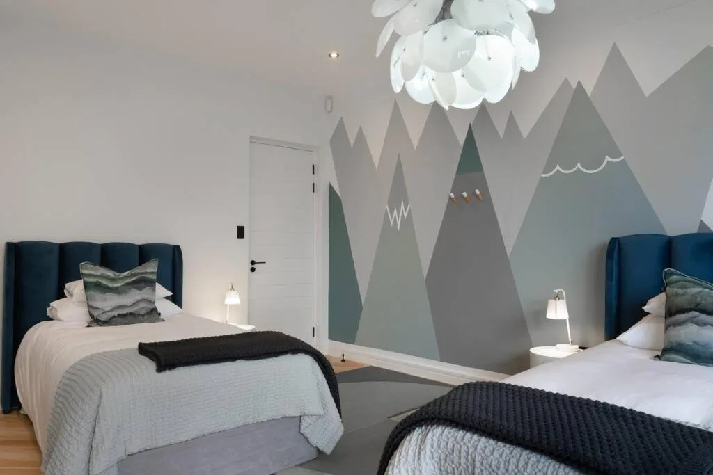 Modern bedroom with two beds and mountain mural wall art