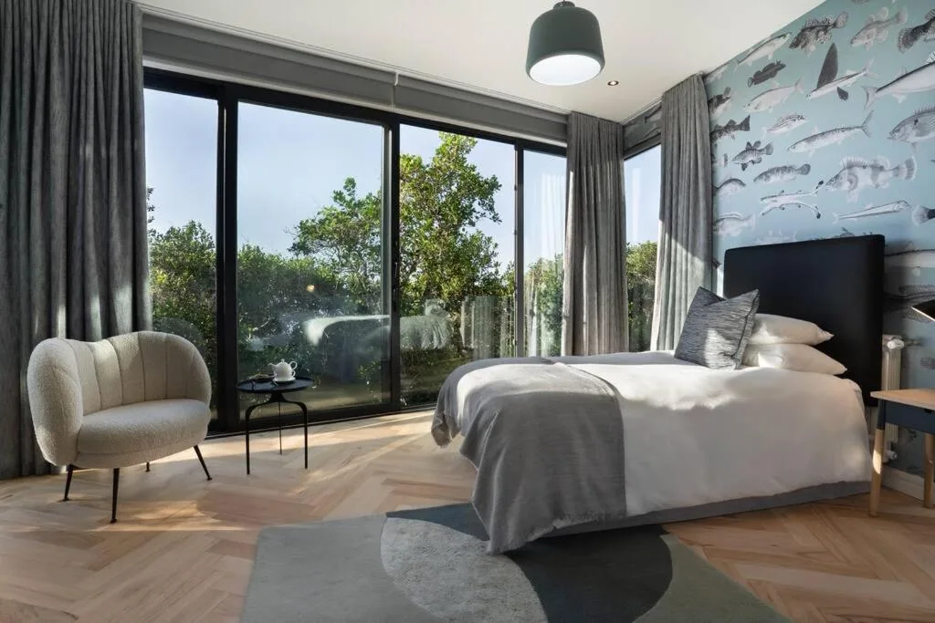 Spacious modern bedroom with queen bed, garden views through large windows