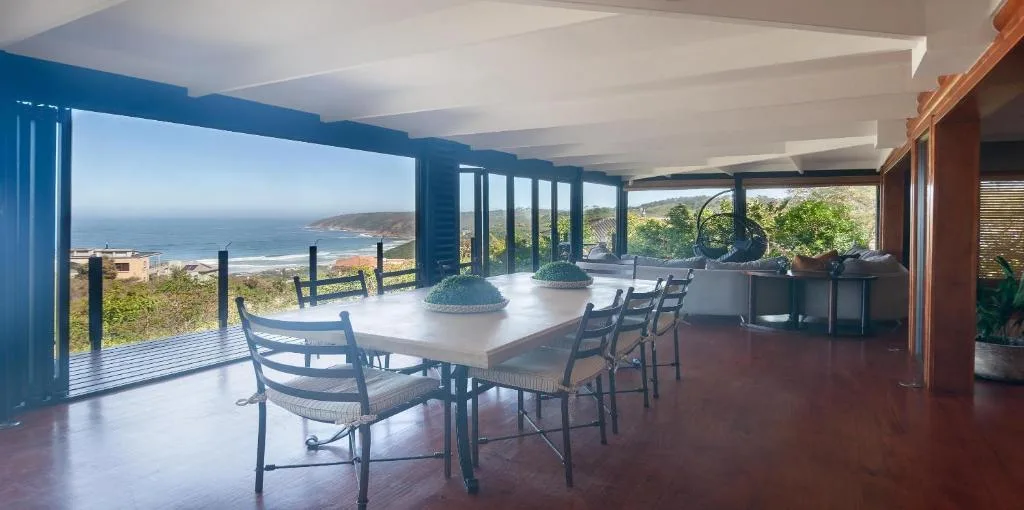 Spacious covered deck with dining table overlooking ocean and coastal landscape