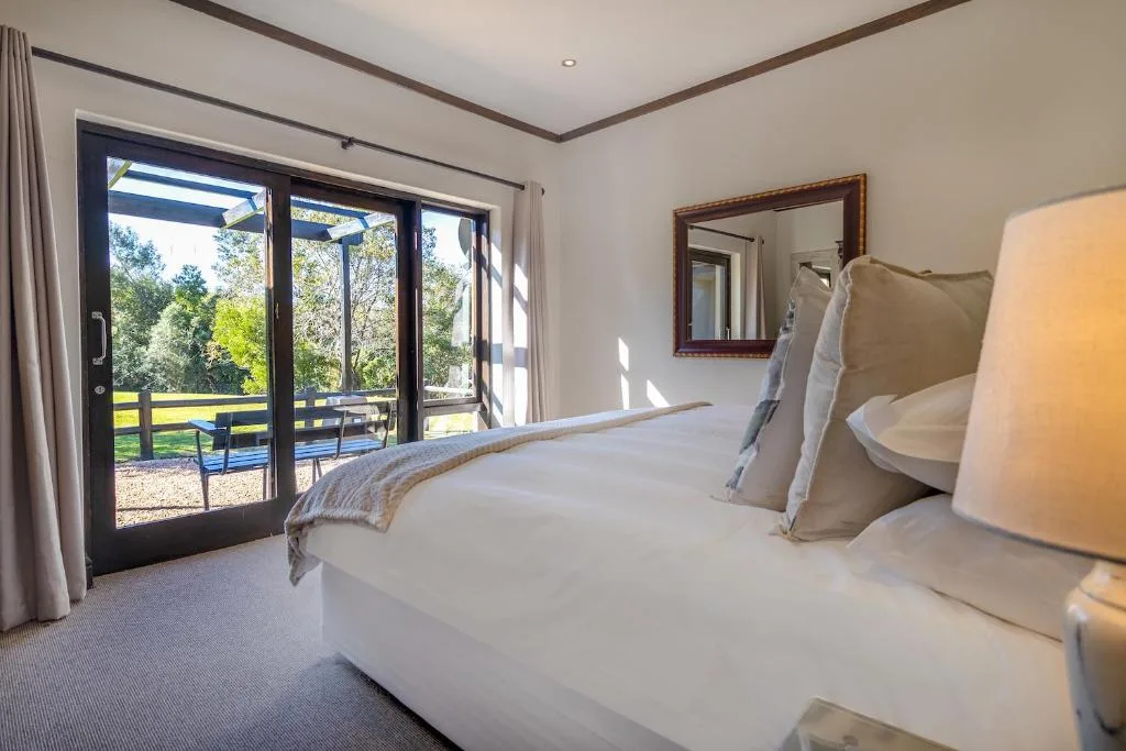 Spacious bedroom with double bed, garden views through glass doors