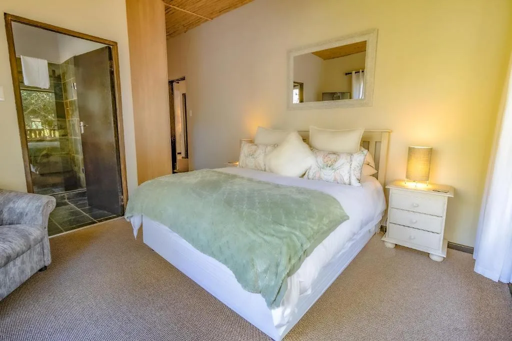 Bright bedroom with queen bed, ensuite bathroom, and warm lighting