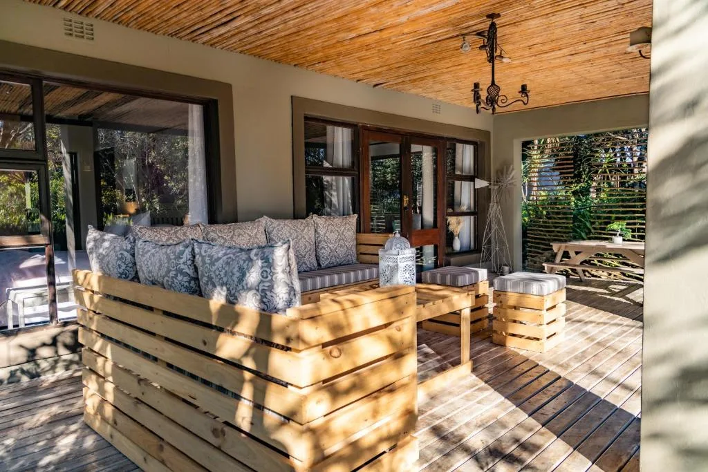 Wooden deck with built-in seating, cushions, and garden views at dusk