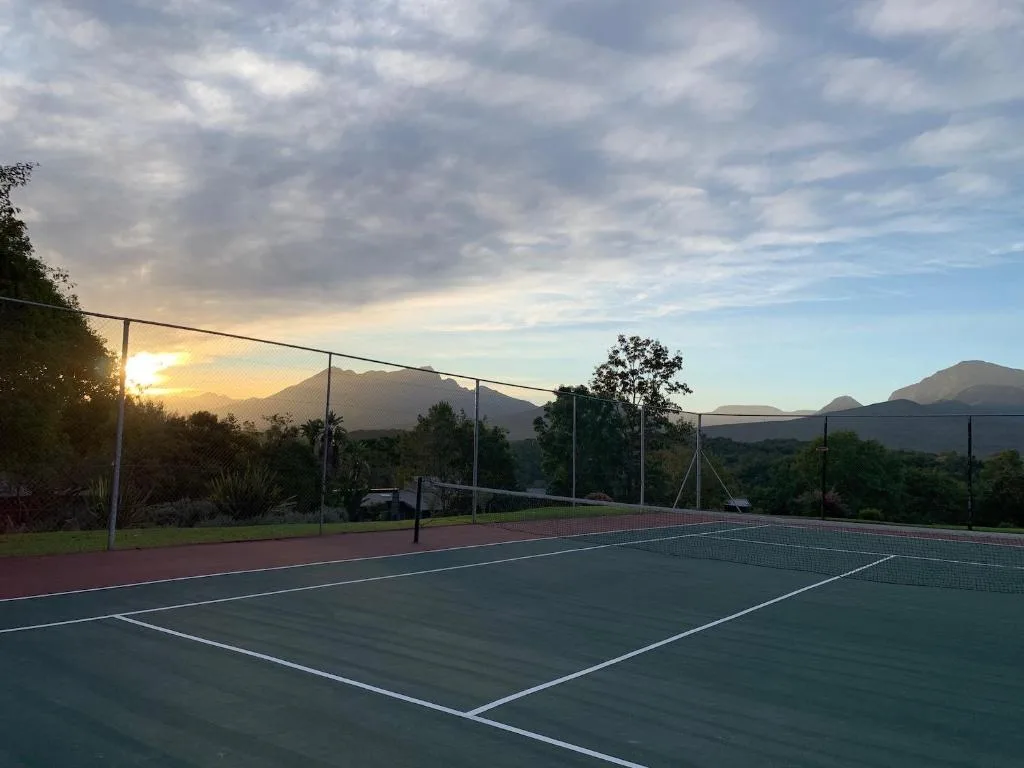 Tennis court at sunset with mountain views and lush vegetation