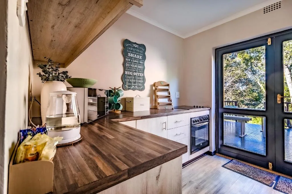 Modern kitchen with wood countertops, white cabinetry, and garden views through French doors