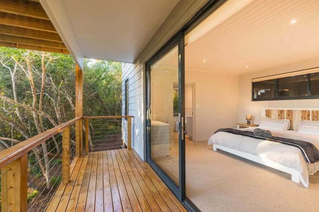 Modern bedroom with dual beds and sliding doors opening to wooden deck