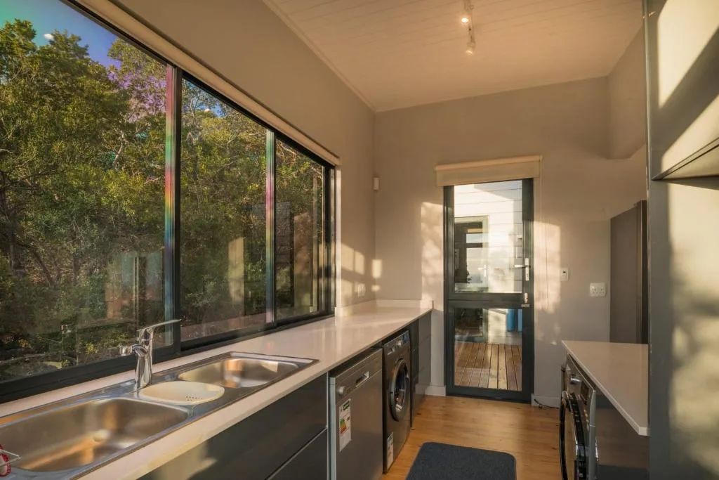 Modern kitchen with stainless steel sink, appliances, and garden views through large windows