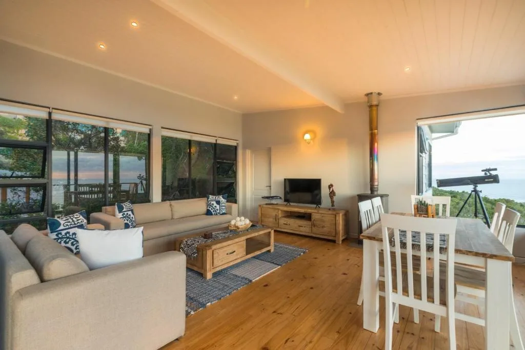 Open-plan lounge with cream sofas, wooden coffee table, and large windows overlooking lagoon