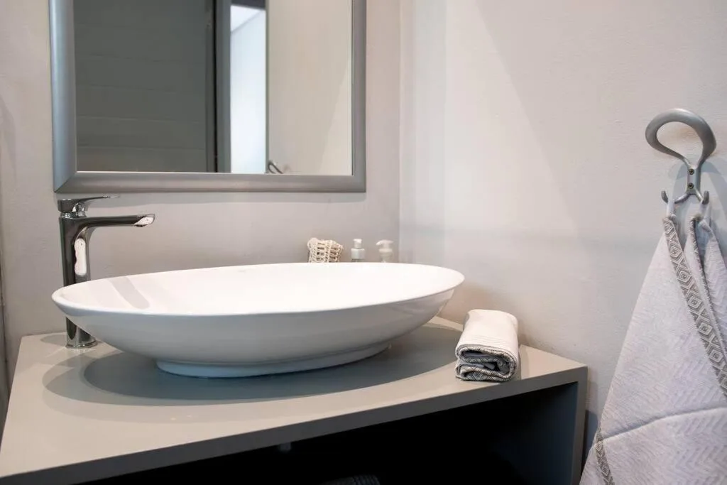 Modern bathroom vanity with oval white basin sink and framed mirror