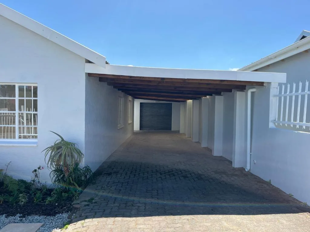 Modern white cottage exterior with covered carport and wooden beams