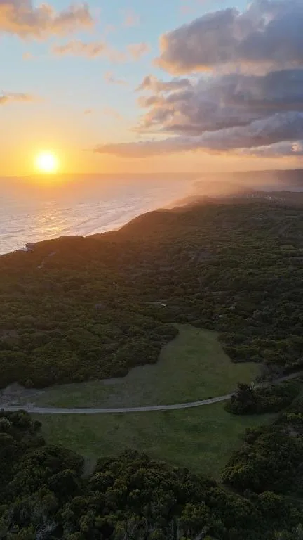 Sunset over ocean and forested coastline with winding river below