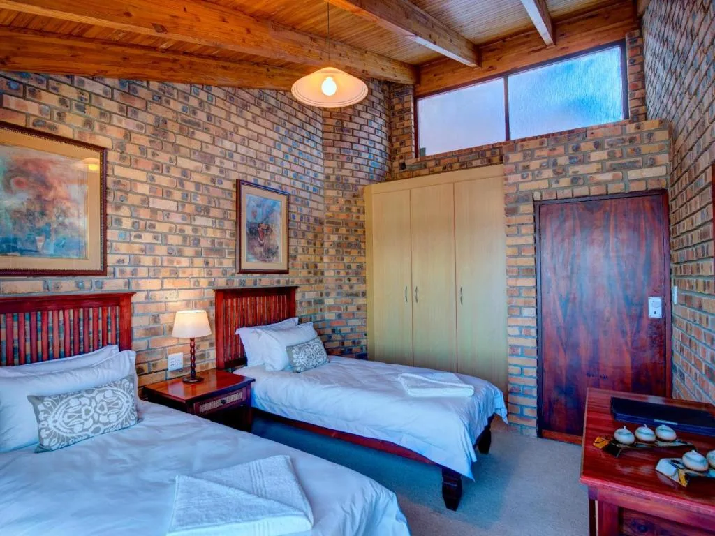 Spacious bedroom with two beds, brick walls, wooden beams, and large windows