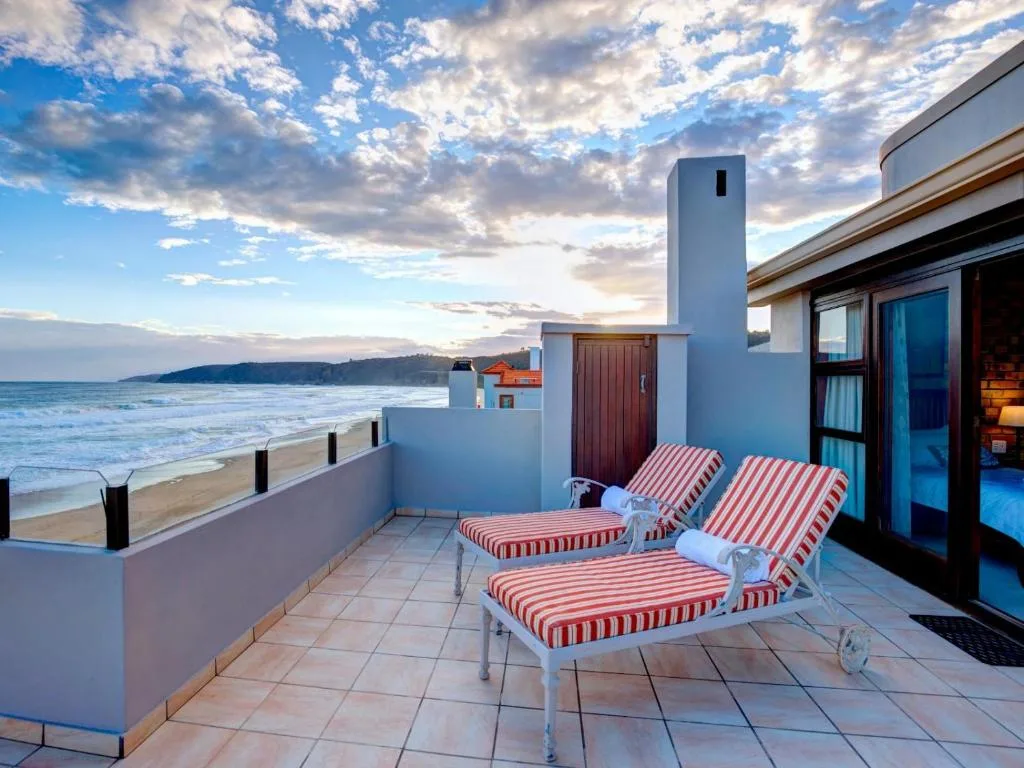 Beachfront patio with striped loungers overlooking ocean and mountains