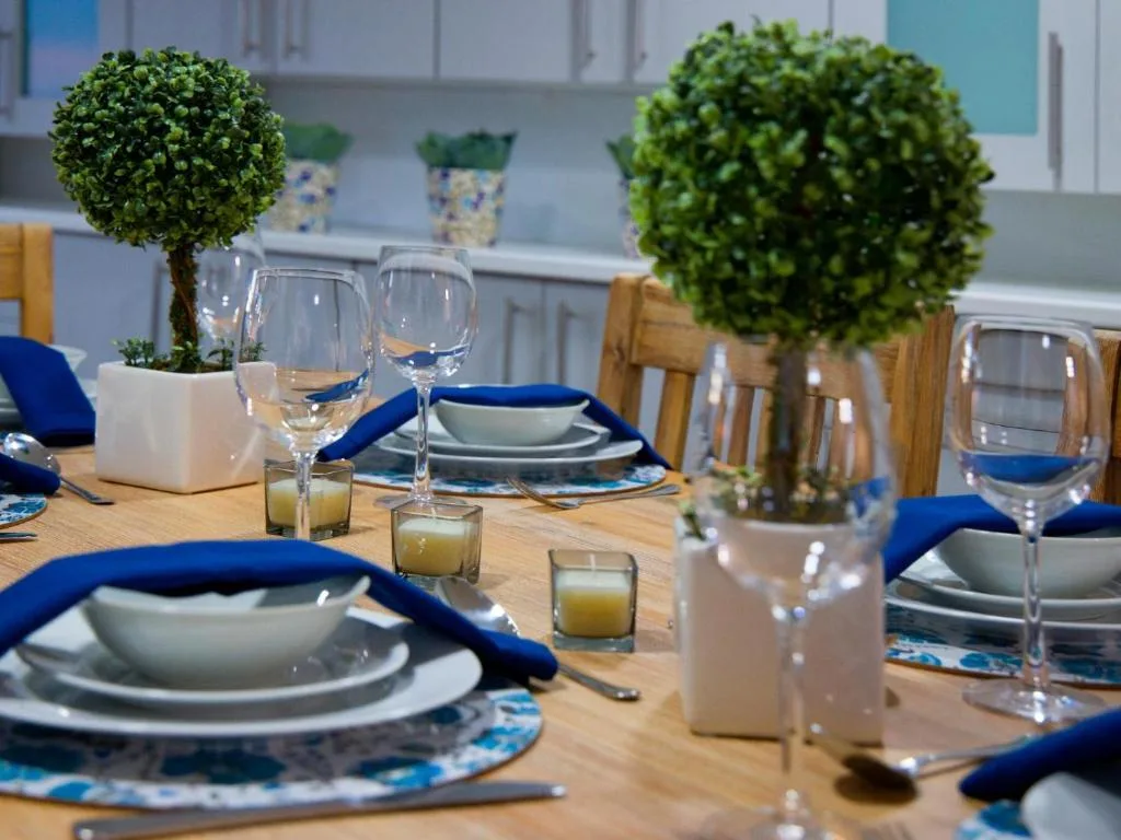 Elegantly set dining table with blue napkins and topiary decorations