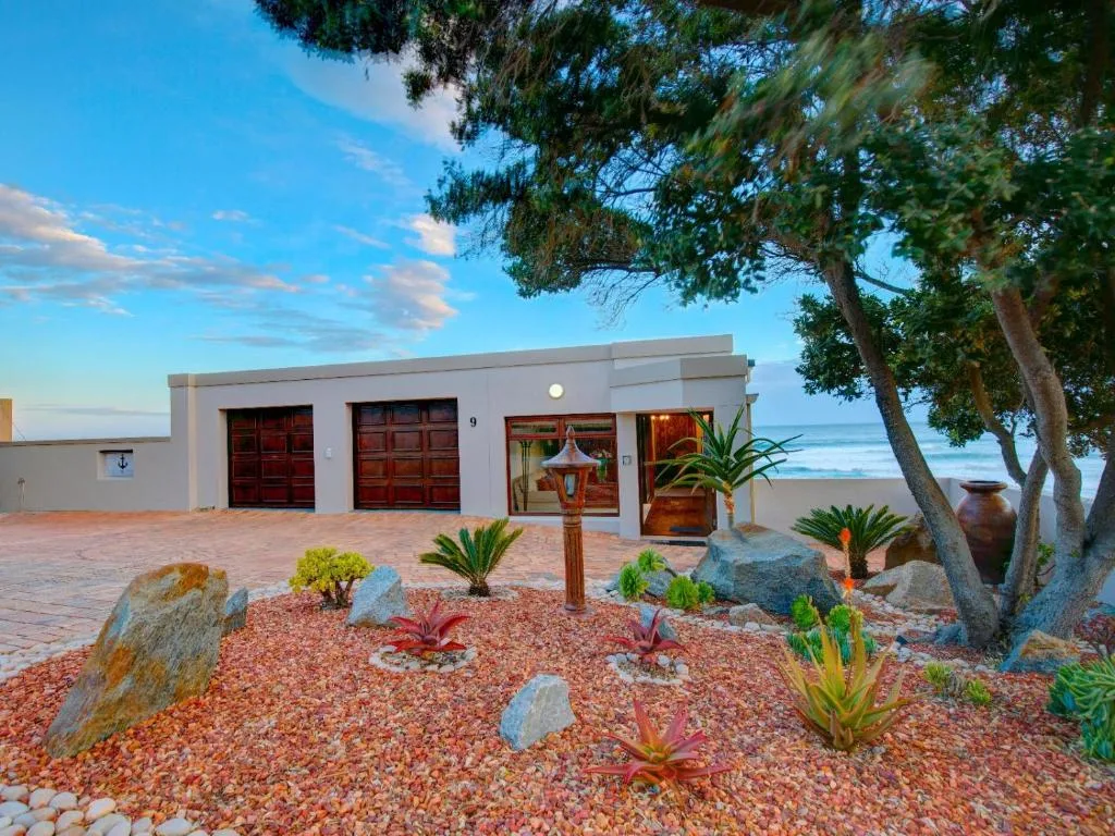 Modern white beachfront villa with red doors and succulent garden landscape