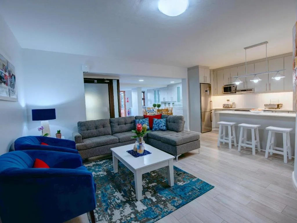 Open-plan lounge with gray sectional sofa, blue armchair, and modern kitchen visible
