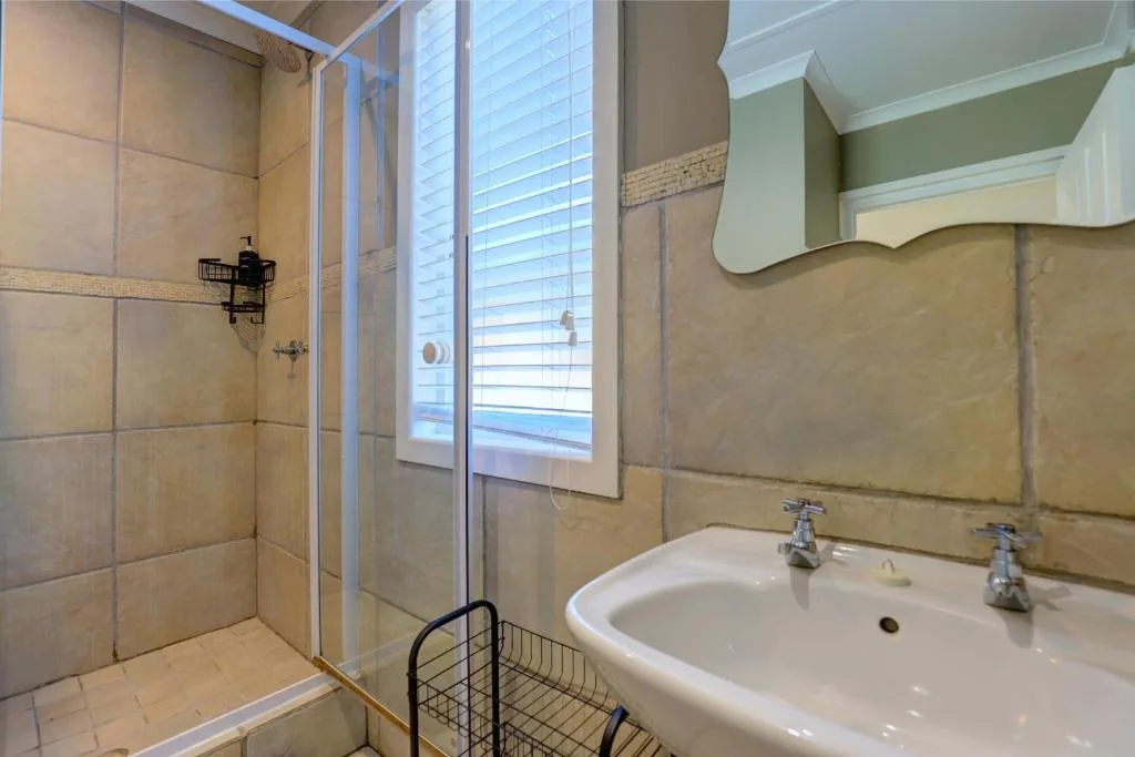 Spacious bathroom with walk-in shower, double vanity sink, and natural light