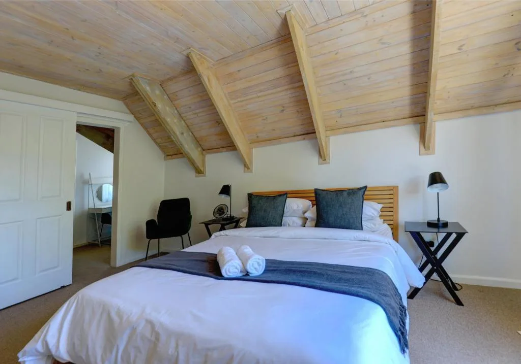 Spacious bedroom with two beds, wooden beam ceiling, and modern amenities