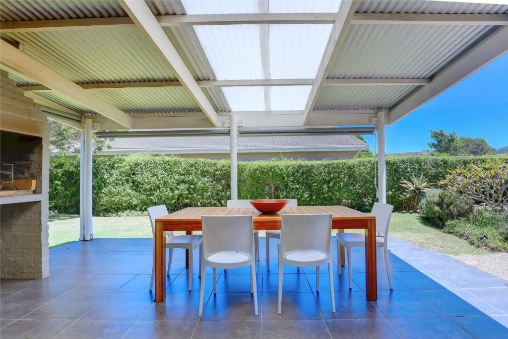 Covered patio with dining table, chairs, and garden views