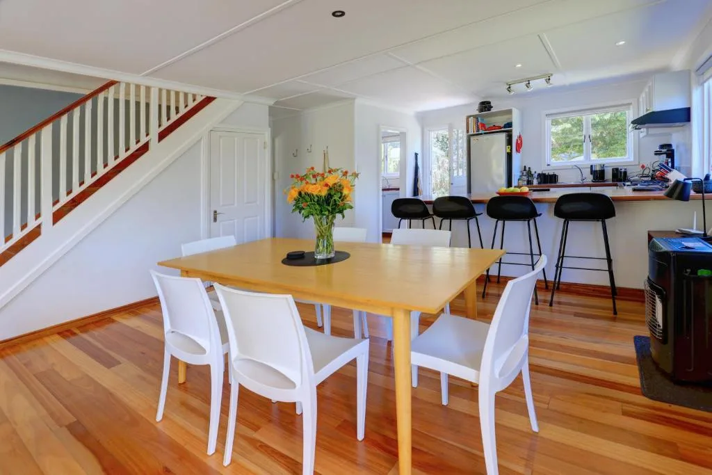Wooden dining table with white chairs and fresh flowers indoors