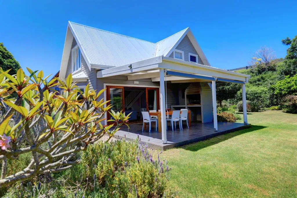 Modern white house with gabled roof and covered deck, green lawn