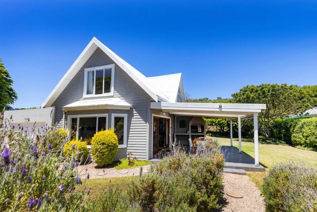 Modern cottage with white trim, pitched roof, and covered porch entrance