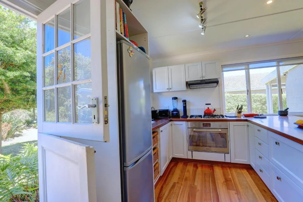 Bright kitchen with white cabinetry, stainless steel appliances, and garden views
