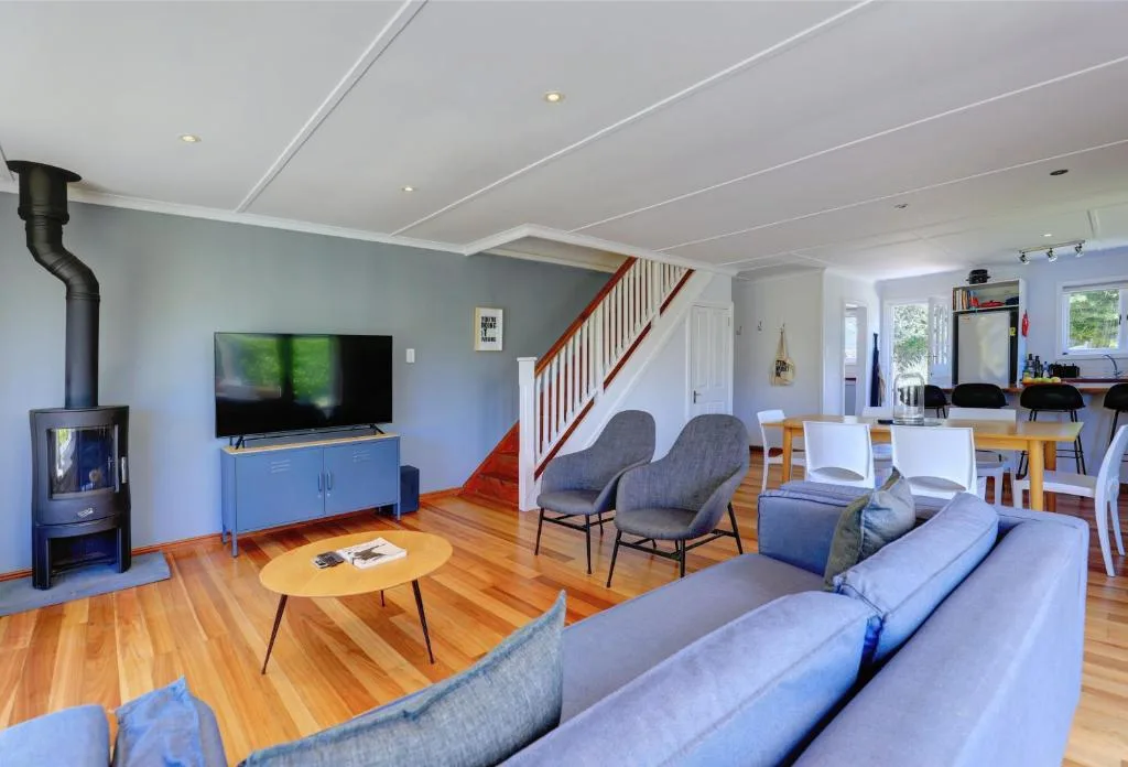 Spacious open-plan lounge with blue sofas, wood floors, fireplace, and TV