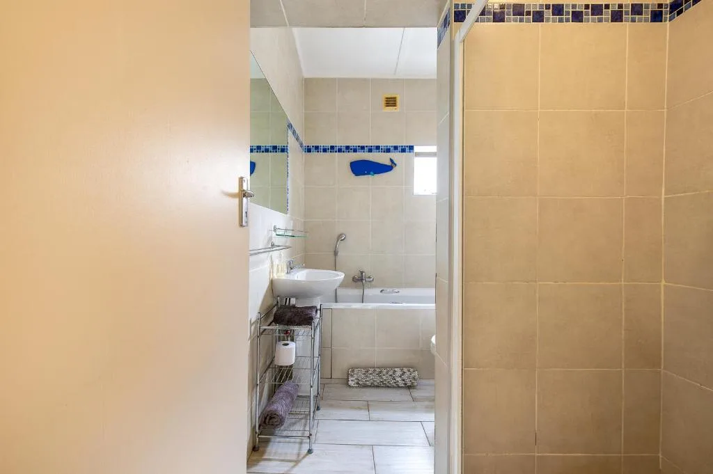 Compact bathroom with white sink, bathtub, and blue tile accents