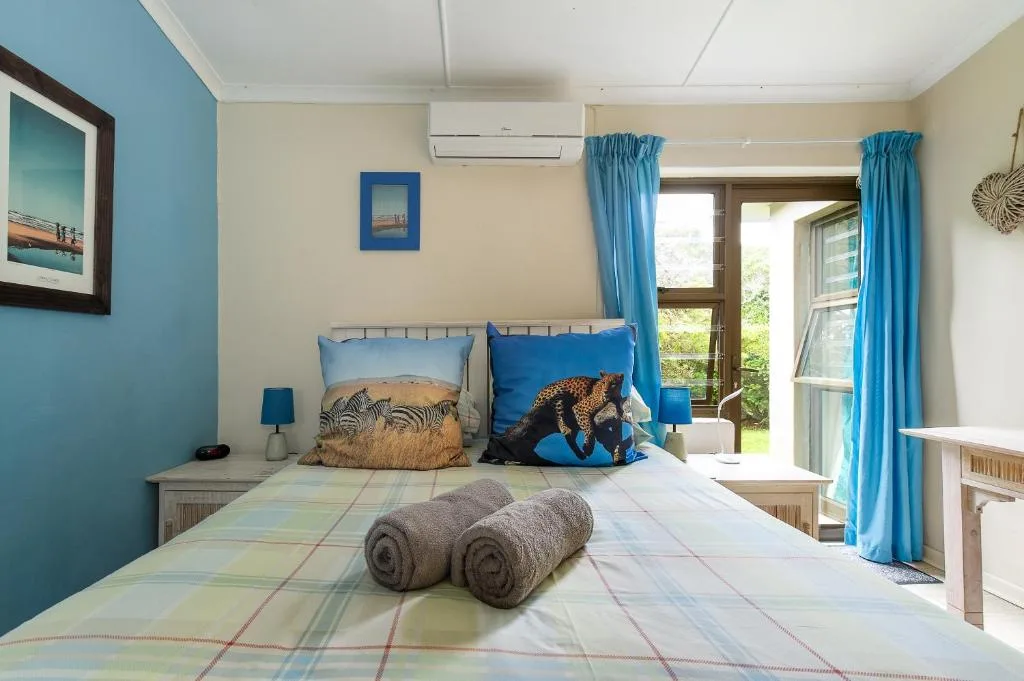 Bright bedroom with double bed, blue accent wall, and garden views through doors