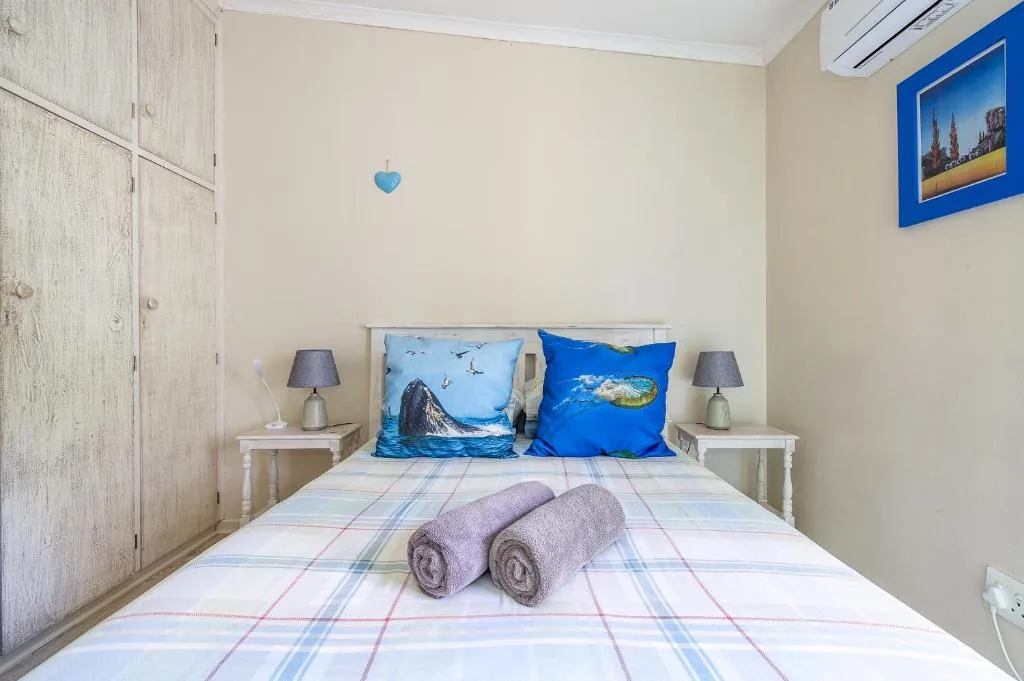 Cozy bedroom with rolled towels on bed and ocean-themed pillows