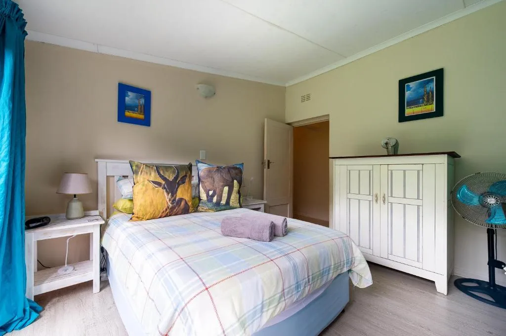 Bright bedroom with double bed, white furniture, and wildlife artwork