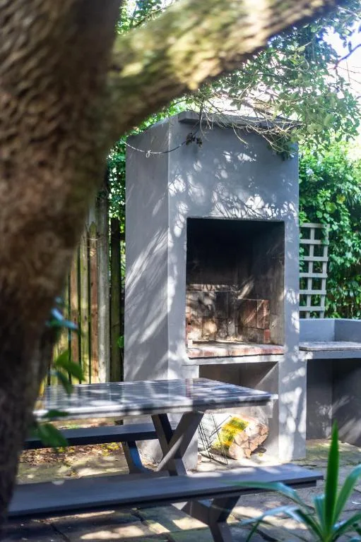 Outdoor braai area with picnic table and fireplace surrounded by greenery