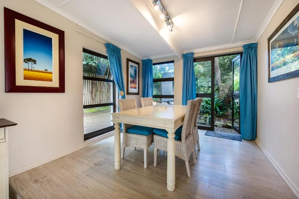 Bright dining area with wooden table, wicker chairs, and garden views