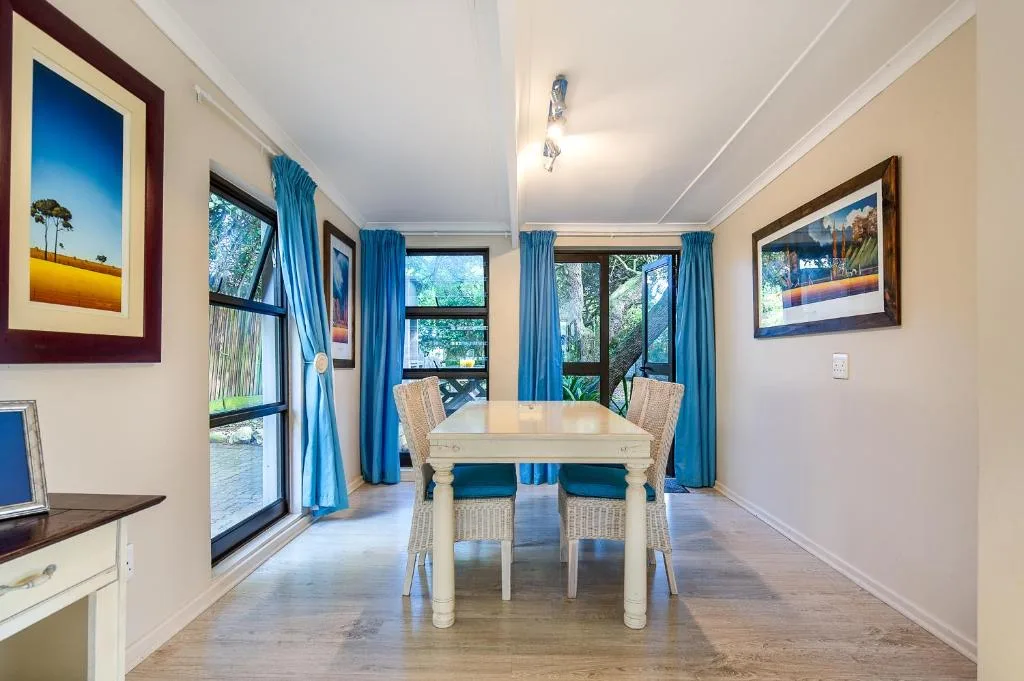 Bright dining area with cream table, wicker chairs, blue curtains, garden views