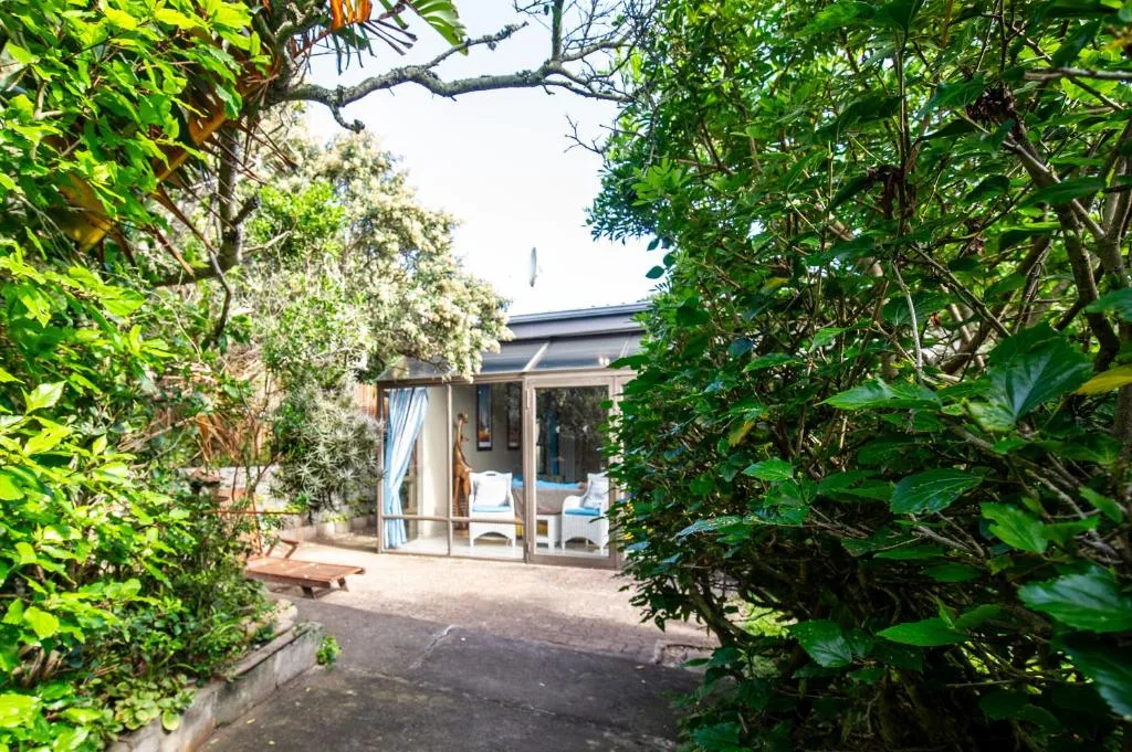 Modern cottage entrance framed by lush green vegetation and trees