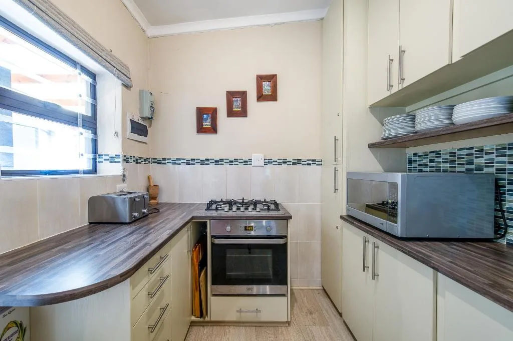 Compact kitchen with gas stove, oven, cream cabinetry and wood countertops