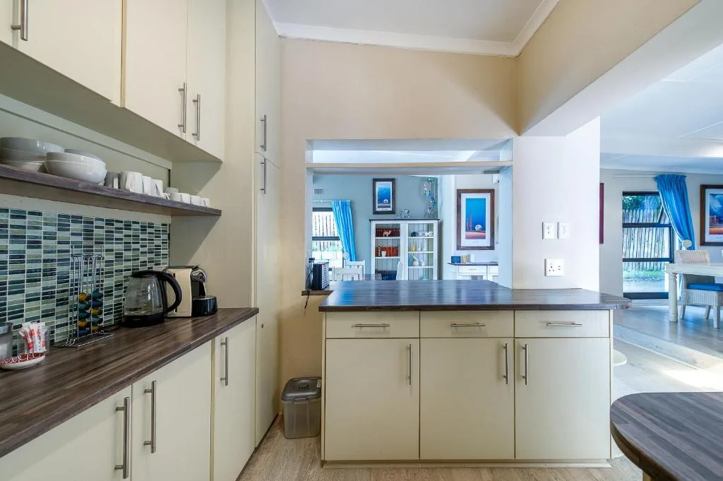 Modern kitchen with cream cabinetry, dark countertop, and green tile backsplash