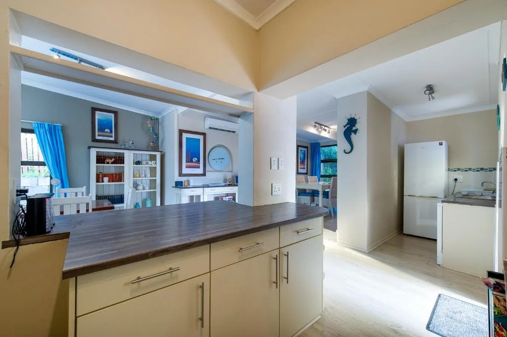 Open-plan kitchen with cream cabinetry, dark countertop, and white refrigerator