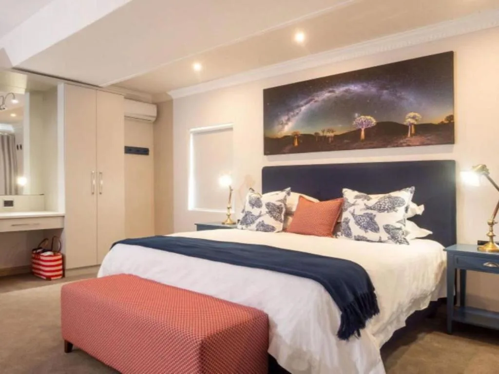 Modern bedroom with queen bed, decorative pillows, and landscape artwork on wall
